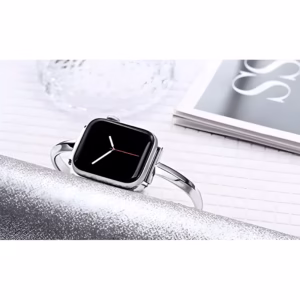 Bracelet Apple Watch EzStrap en métal inoxydable, style élégant avec finition lisse demi-jonc et chaînette, posé sur une surface scintillante à côté d’un verre et d’un magazine.