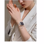Bracelet Apple Watch EzStrap en métal inoxydable, style élégant demi-jonc à chaînette, finition lisse, porté au poignet d’une femme habillée en veste blanche.