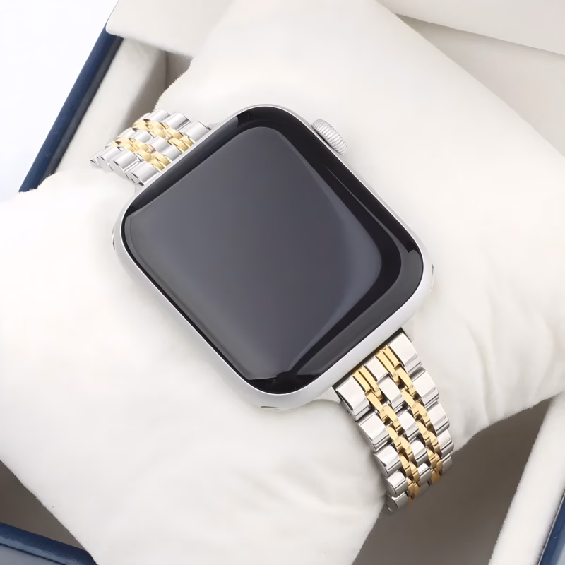 Bracelet Apple Watch EzStrap en métal inoxydable au design lisse et raffiné, style luxe avec maillons bicolores argent et or, présenté sur un coussin blanc dans un coffret.