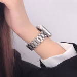 Bracelet Apple Watch EzStrap en métal inoxydable à maillons lisses, de style élégant, porté au poignet d'une femme en tenue professionnelle.