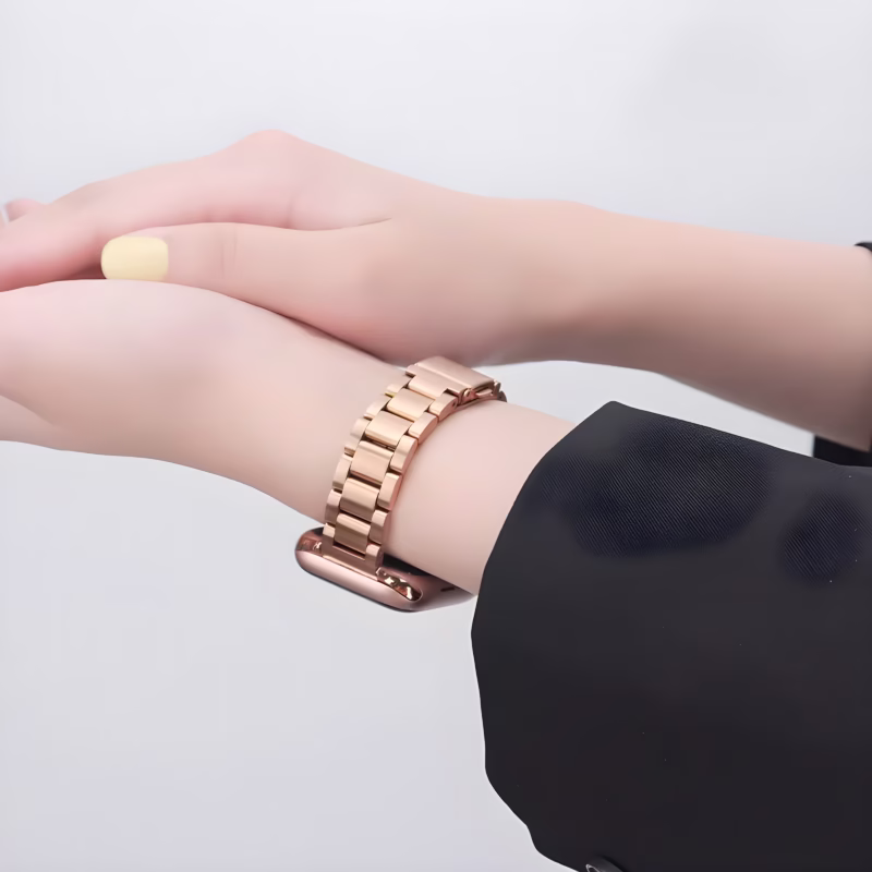 Bracelet Apple Watch EzStrap en métal rose doré à maillons classiques, au style élégant et à finition lisse, porté au poignet d’une femme en veste noire.