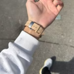 Bracelet Apple Watch EzStrap en cuir véritable lisse de couleur beige, style élégant avec boucle déployante en métal, porté au poignet d’une personne en extérieur.