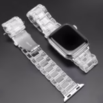 Bracelet Apple Watch EzStrap en plastique transparent à maillons articulés, au style élégant et à la finition lisse, présenté à plat sur une surface noire.