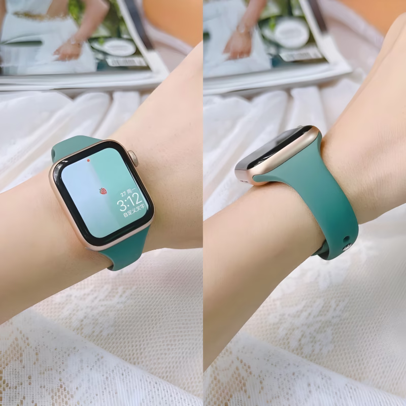 Bracelet Apple Watch EzStrap en silicone lisse vert, au style sport, porté au poignet d’une femme sur un fond en dentelle avec un magazine en arrière-plan.