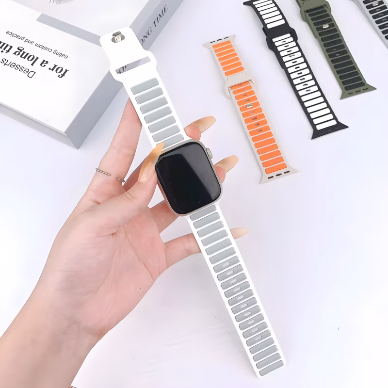 Bracelet Apple Watch EzStrap en silicone perforé de style sport, blanc avec inserts gris texturés, tenu à la main sur fond blanc.