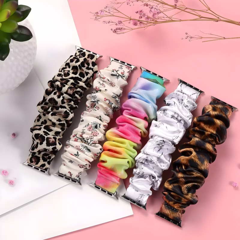 Bracelet Apple Watch EzStrap en textile élastique style chouchou, au design texturé et motifs variés comme léopard, floral et dégradé, présenté à plat sur un fond rose avec des éléments décoratifs.