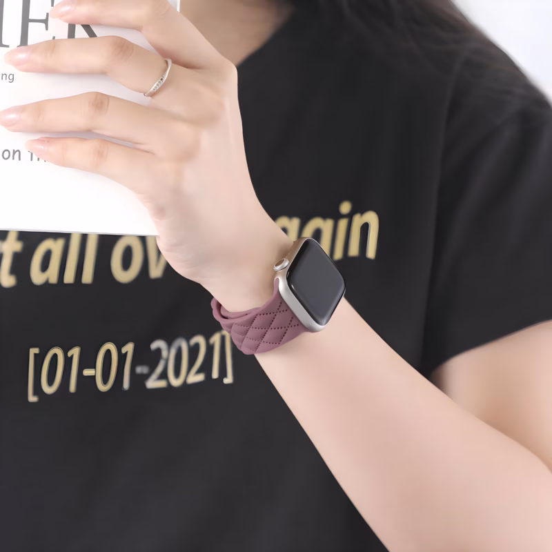 Bracelet Apple Watch EzStrap en silicone matelassé de style élégant, porté au poignet d’une femme tenant un livre.