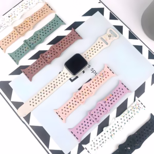 Bracelet Apple Watch EzStrap en silicone perforé au style sport avec éclats multicolores, posé à plat sur un magazine graphique aux côtés d’autres modèles colorés.