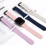 Bracelet Apple Watch EzStrap en silicone lisse, style sport, présenté en plusieurs coloris posés à plat sur un magazine.