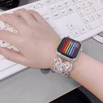 Bracelet Apple Watch EzStrap en métal scintillant de style luxe, avec maillons décoratifs sertis de cristaux, porté au poignet d’une femme en train de taper sur un clavier.