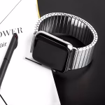 Bracelet Apple Watch EzStrap en métal brossé, élégant et à maillons flexibles extensibles, posé sur une table noire à côté d’un stylo et d’un carnet.