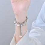 Bracelet Apple Watch EzStrap en métal argenté orné de perles brillantes, au style élégant et scintillant, porté au poignet d’une femme vêtue d’un chemisier blanc.