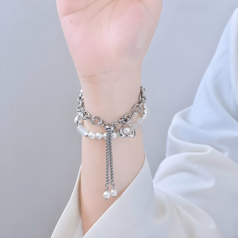 Bracelet Apple Watch EzStrap en métal argenté orné de perles brillantes, au style élégant et scintillant, porté au poignet d’une femme vêtue d’un chemisier blanc.
