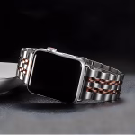 Bracelet Apple Watch EzStrap en acier inoxydable style Jubilee, finition brossée et brillante, look premium avec maillons argentés et dorés, posé sur une surface sombre.