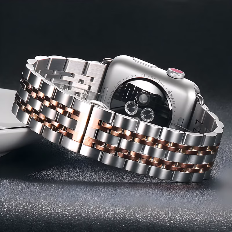 Bracelet Apple Watch EzStrap en acier inoxydable style Jubilee, finition brossée et brillante, posé sur une surface noire à côté d’un iPhone.