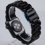 Bracelet Apple Watch EzStrap en métal noir à maillons articulés, au style élégant et finition lisse, présenté en gros plan sur un présentoir transparent.