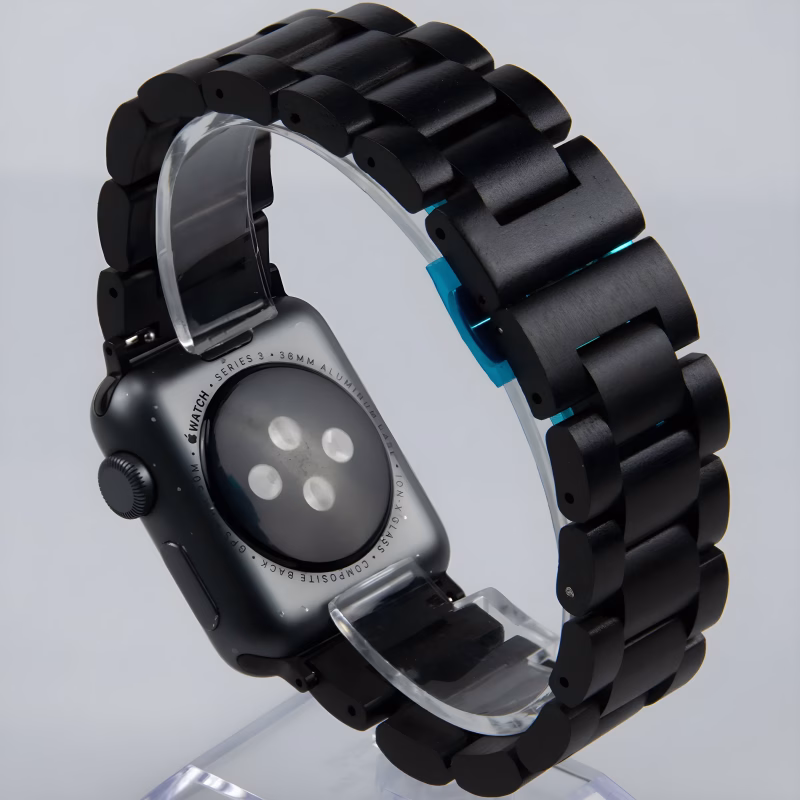 Bracelet Apple Watch EzStrap en métal noir à maillons articulés, au style élégant et finition lisse, présenté en gros plan sur un présentoir transparent.