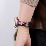 Bracelet Apple Watch EzStrap en cuir lisse à motif floral imprimé, au style élégant, porté au poignet d’une femme vêtue d’un pull beige.