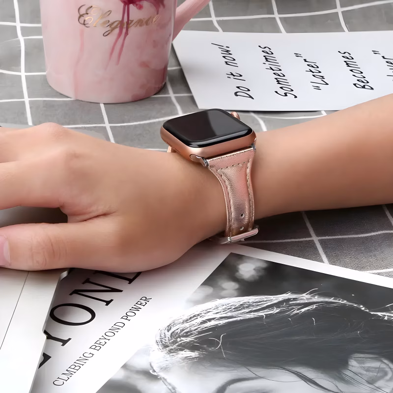 Bracelet Apple Watch EzStrap en cuir lisse imprimé à finition scintillante, de style élégant, porté au poignet d’une femme, posé sur une table avec une tasse rose et un magazine.