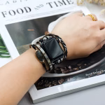 Bracelet Apple Watch EzStrap en cuir multibrins avec ornements métalliques brillants, style élégant et artisanal, porté au poignet d’une personne lisant un magazine.