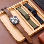 Bracelet Apple Watch EzStrap en cuir véritable grainé à doublure silicone, style premium, présenté en trois coloris sur un plateau en bois.