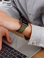 Bracelet Apple Watch EzStrap en cuir véritable grainé avec intérieur en silicone, style élégant, porté au poignet d’un homme utilisant un ordinateur portable.