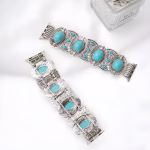 Bracelet Apple Watch EzStrap en métal alliage de zinc, de style artisanal élégant, orné de pierres turquoises serties avec un design gravé et texturé, présenté à plat sur un tissu blanc à côté d’un pot décoratif.