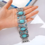 Bracelet Apple Watch EzStrap en métal, de style élégant et artisanal, orné de pierres turquoises serties et au design gravé et texturé, présenté dans la paume d'une main sous une lumière naturelle.