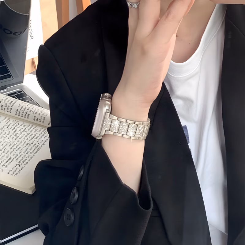Bracelet Apple Watch EzStrap en métal, structure articulée brillante avec finition scintillante, porté au poignet d’une personne en veste noire.