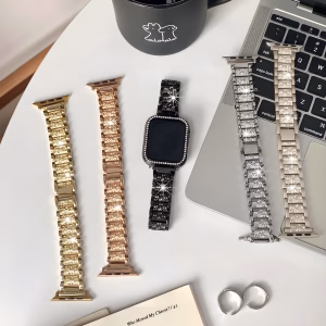 Bracelet Apple Watch EzStrap en alliage de zinc brillant, style luxe scintillant, posé sur une table blanche à côté d’un ordinateur portable et d’une tasse noire.