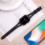 Bracelet Apple Watch EzStrap en cuir lisse noir avec fente ornementale, style élégant, posé sur une feuille imprimée près d’un smartphone et d’une tasse.