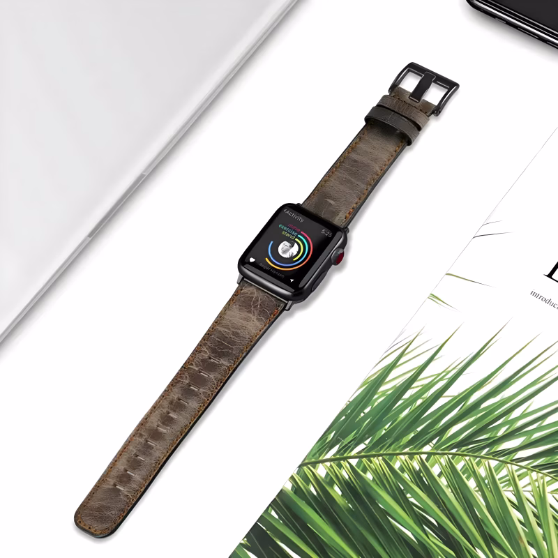 Bracelet Apple Watch EzStrap en cuir patiné au design traditionnel, style élégant avec effet texturé mat, posé sur un bureau entre un ordinateur et un magazine.