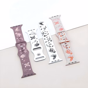 Bracelet Apple Watch EzStrap en silicone à motif floral et oiseau stylisé, de style artisanal, présenté en gros plan sur une surface bicolore.