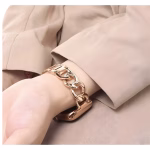 Bracelet Apple Watch EzStrap en métal doré au design maillons géométriques et ovales, porté au poignet d’une personne vêtue d’une chemise beige.