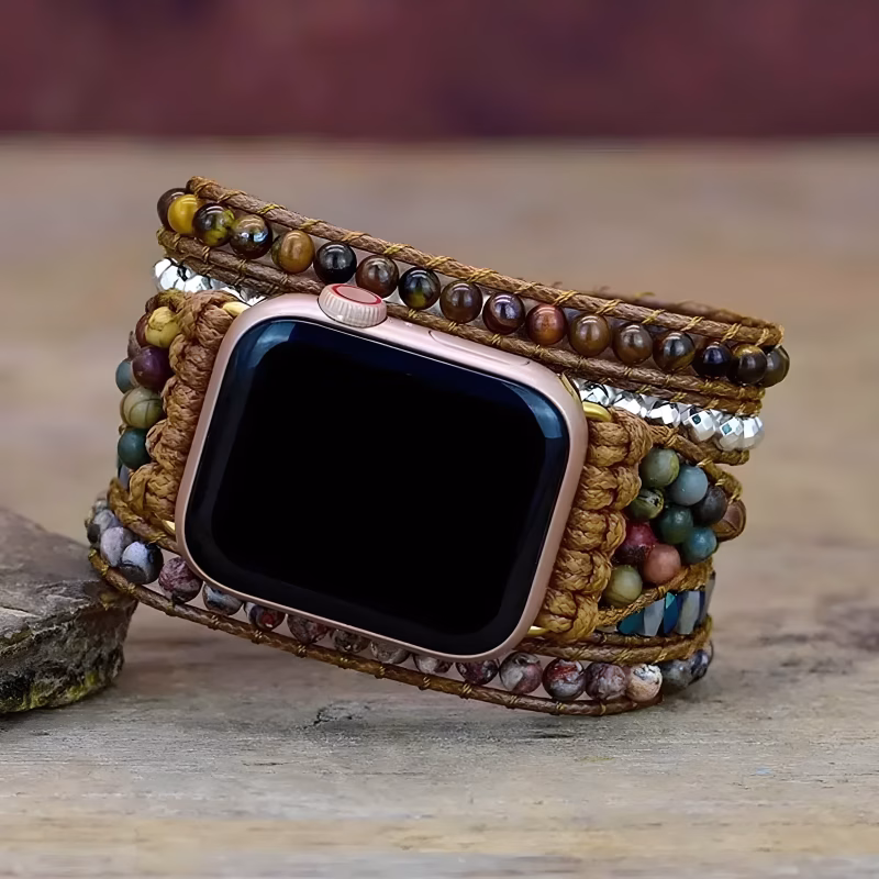 Bracelet Apple Watch EzStrap multi-couches en cuir tressé artisanal avec perles colorées et détails en métal, posé sur une surface en bois rustique.