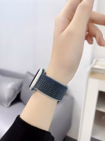 Bracelet Apple Watch EzStrap en nylon texturé de style sport, porté au poignet d'une femme devant un canapé gris.