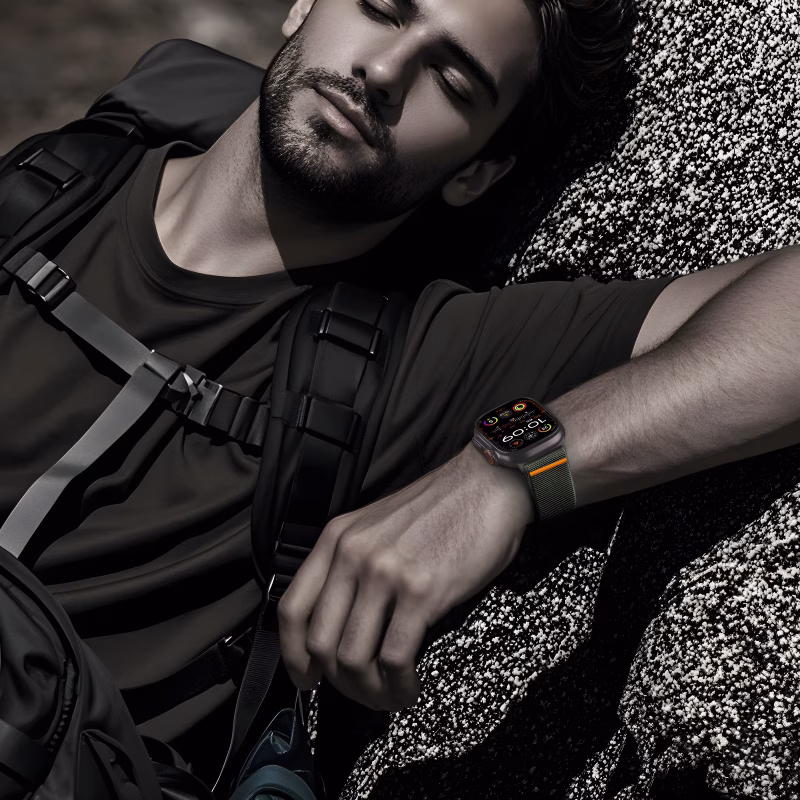 Bracelet Apple Watch EzStrap en nylon texturé de style sport, avec boucle à clip parachute, porté au poignet d’un homme allongé en tenue de randonnée.
