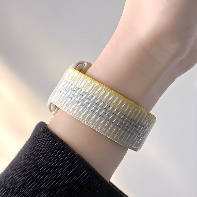 Boucle Sport Apple Watch EzStrap, avec scratch réglable, porté au poignet d’une personne vêtue de noir.