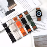 Bracelet Apple Watch EzStrap en nylon texturé de style sport, décliné en plusieurs coloris, posé sur des feuilles de magazine avec une montre en présentation.