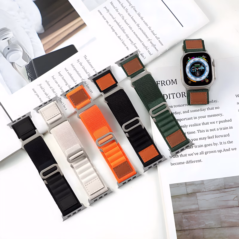 Bracelet Apple Watch EzStrap en nylon texturé de style sport, décliné en plusieurs coloris, posé sur des feuilles de magazine avec une montre en présentation.