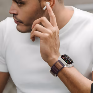 Bracelet Apple Watch EzStrap en nylon texturé, style sport avec design Alpine Loop, porté au poignet d’un homme en t-shirt blanc utilisant un écouteur sans fil.