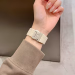 Bracelet Apple Watch EzStrap en nylon tressé beige au style sport et à texture texturée, porté au poignet d’une femme en pull beige.