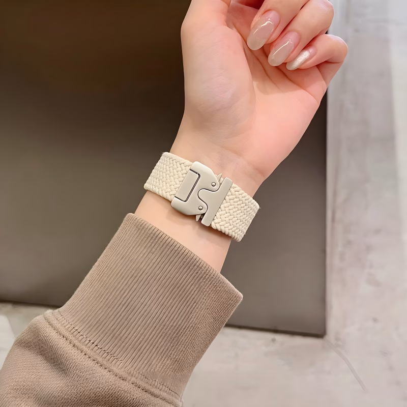Bracelet Apple Watch EzStrap en nylon tressé beige au style sport et à texture texturée, porté au poignet d’une femme en pull beige.