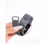 Bracelet Apple Watch EzStrap en plastique texturé de style sport, tressé en nylon gris, tenu entre les doigts en gros plan.