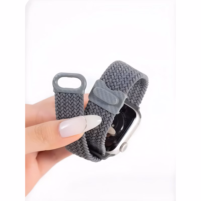 Bracelet Apple Watch EzStrap en plastique texturé de style sport, tressé en nylon gris, tenu entre les doigts en gros plan.