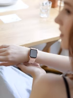 Bracelet Apple Watch EzStrap en nylon texturé, style sport, avec boucle réglable, porté au poignet d’une femme assise à une table en bois.