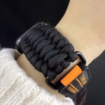 Bracelet Apple Watch EzStrap en nylon tressé noir de style sport, avec détails texturés façon paracorde, porté au poignet d’une personne habillée d’un pull en maille clair.