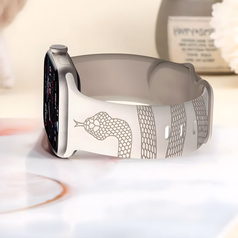 Bracelet Apple Watch EzStrap en silicone gravé, style sport, avec motif serpent stylisé, posé sur une surface brillante près d’un vase décoratif.