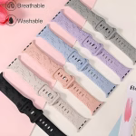 Bracelet Apple Watch EzStrap en silicone gravé, style sport avec motifs Disney en relief, présenté en plusieurs coloris pastel et noir, disposés à plat sur une surface rose et beige.