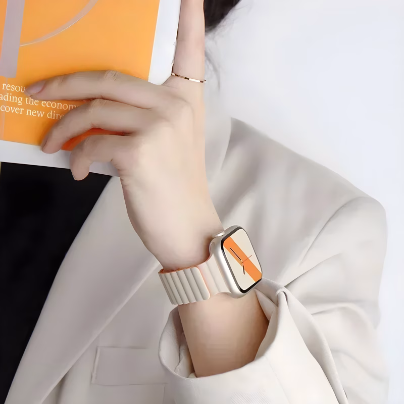 Bracelet Apple Watch EzStrap en silicone blanc au design ondulé, style sport, porté au poignet d’une femme vêtue d’un blazer clair tenant un magazine.